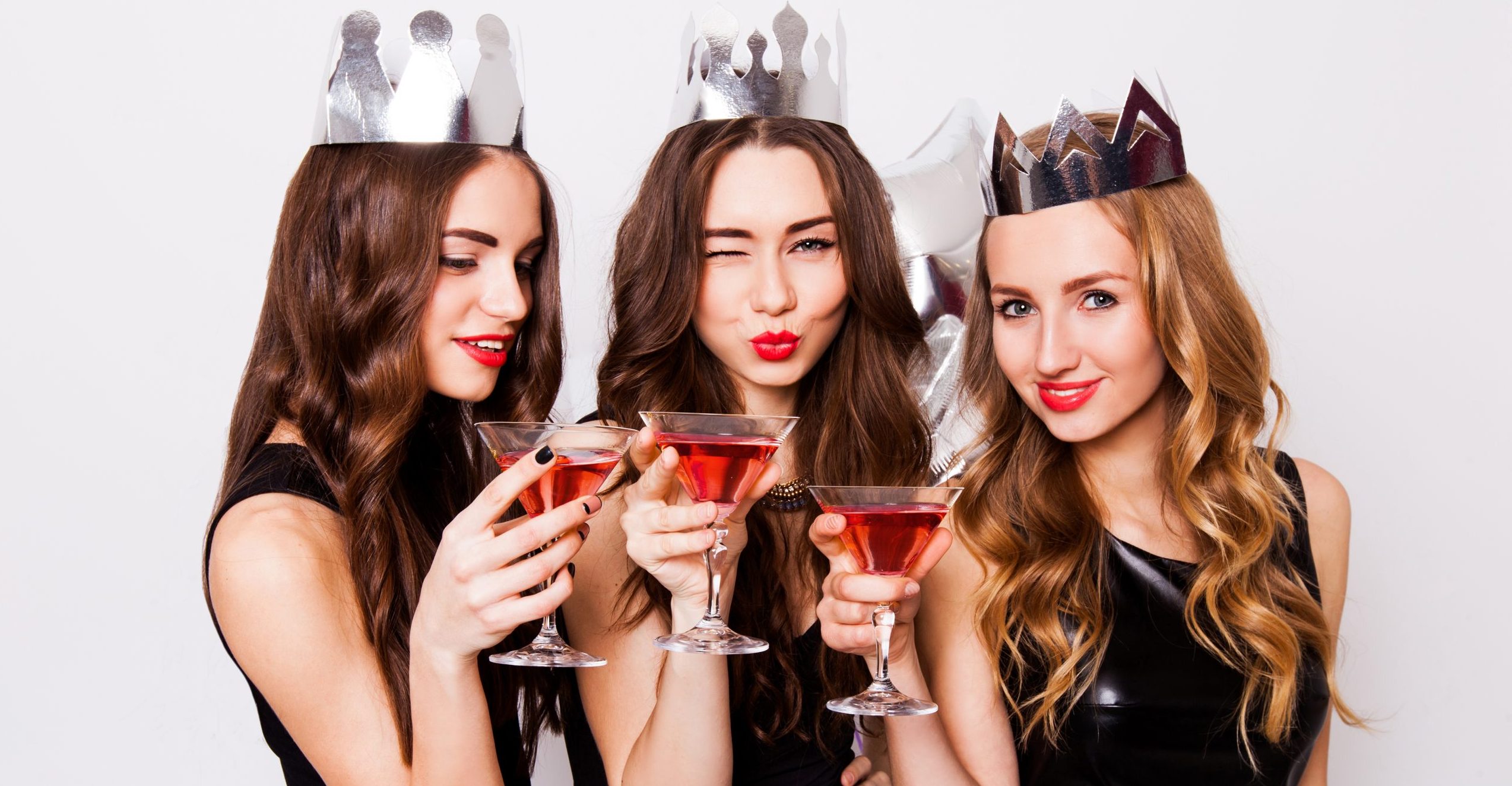 three-beautiful-elegant-women-celebrate-hen-party-and-drinking-cocktails-best-friends-wearing-black-evening-dress-crown-on-head-and-clink-glasses-bright-make-up-red-lips-inside