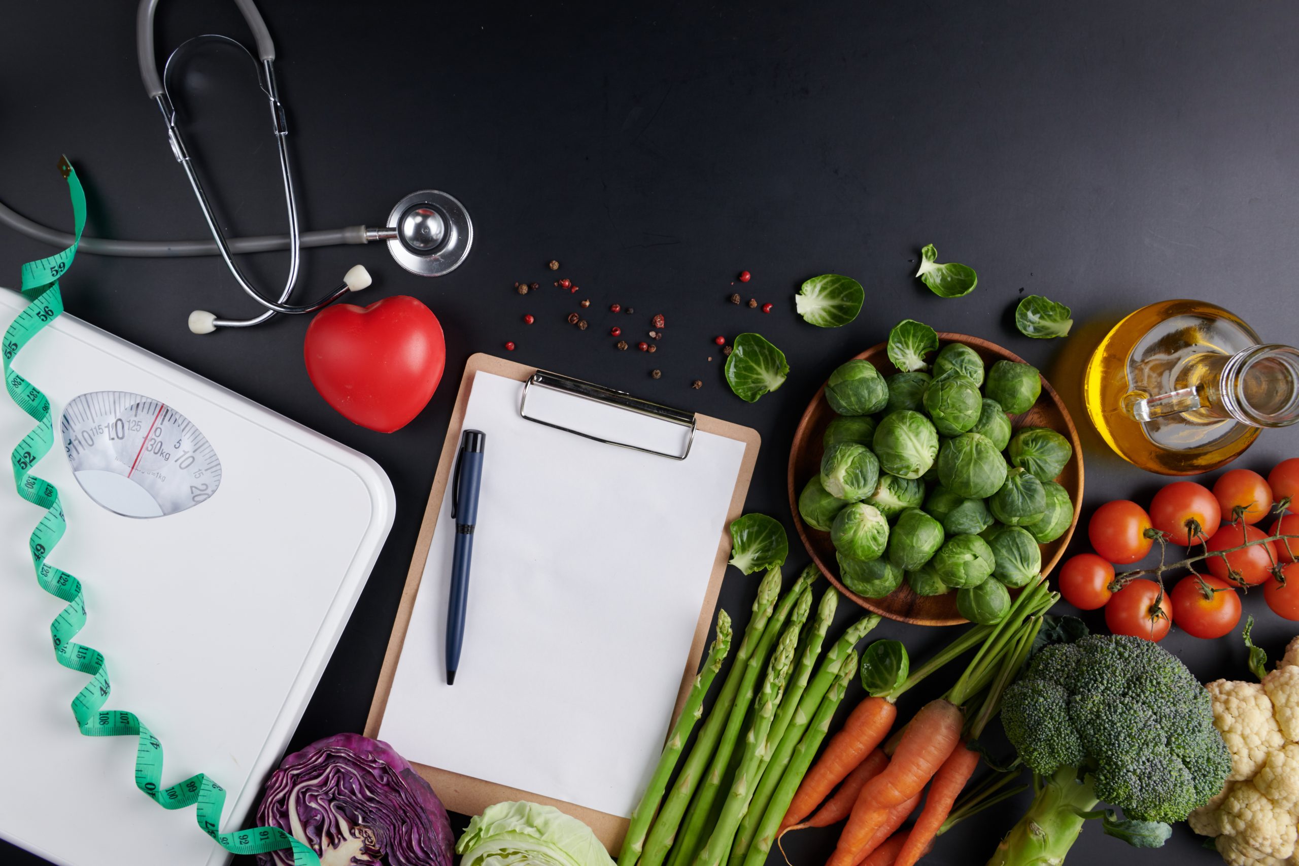 Weight loss scale with centimeter, stethoscope, Dumbbell, Clipboard, pen. Diet concept. Healthy food background. different fruits and vegetables, nuts. concept slimming diet fresh vegetables.