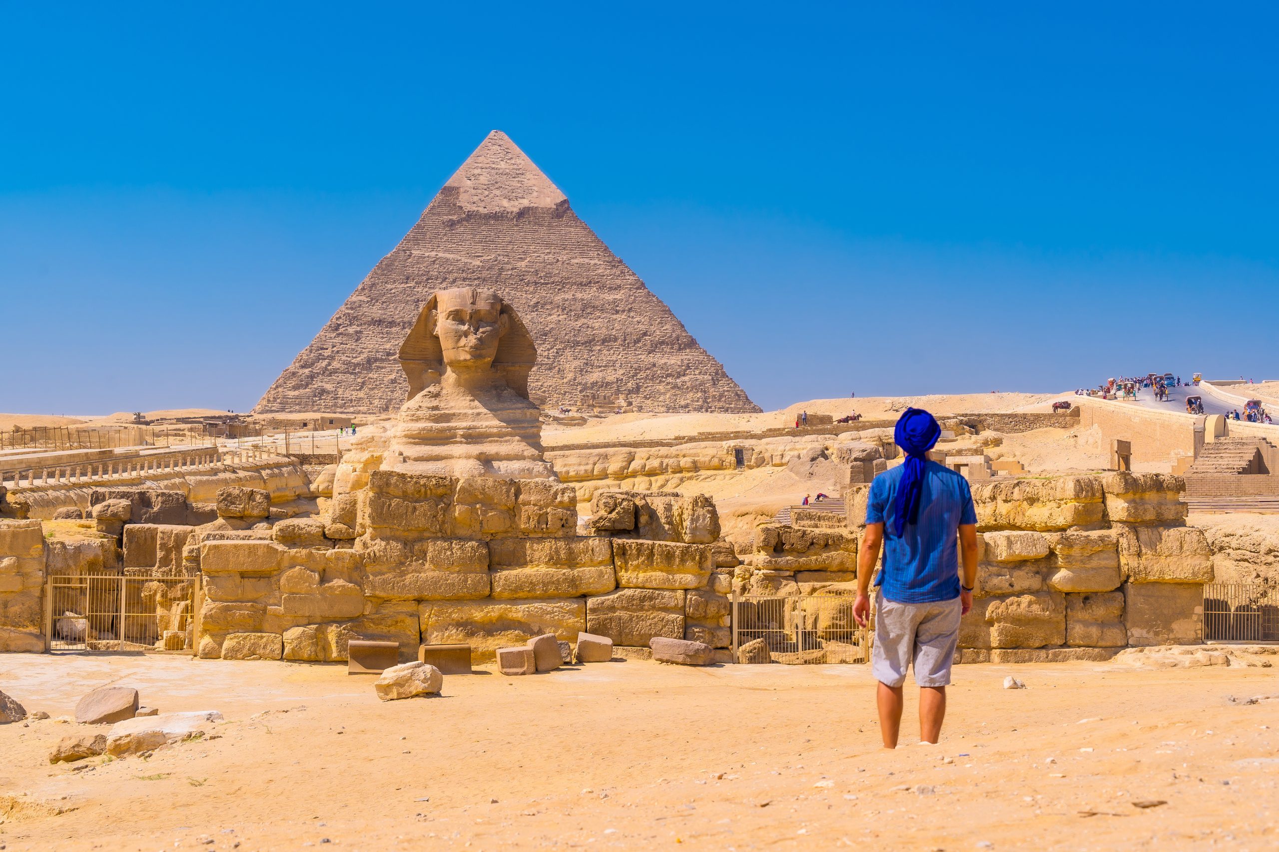 A young man walking towards the Great Sphinx of Giza and in the background the pyramid of Khafre,