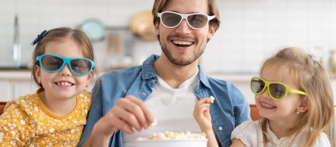 Happy family watching TV at home and eating popcorn