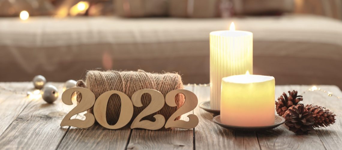 Home Christmas composition with decorative wood 2022 numbers, candles, and decor details on a blurred room interior background.