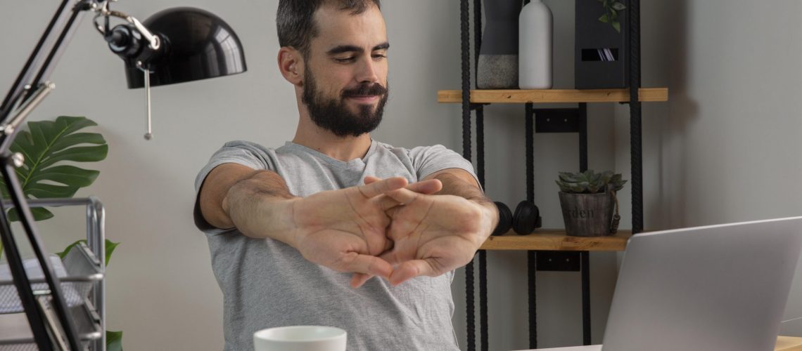 man-stretching-his-arms-while-working-from-home